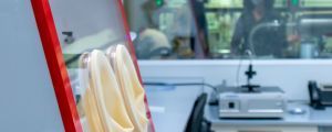 One of the laboratories at ICMAB. Two people behind a glass window watch a glove box.