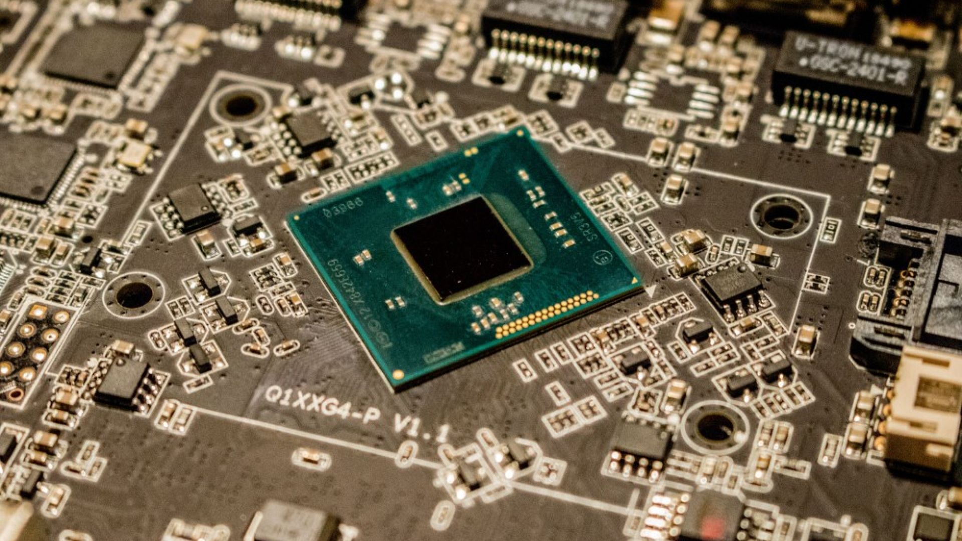 Detailed view of a microchip on a printed circuit board, showcasing electronic components | Jeremy Waterhouse, Unsplash