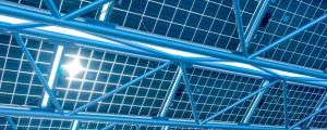 A picture of solar panels, with the sun shining through them.
